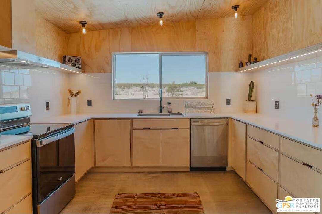 4619 Kickapoo Trail Landers, CA 92285 - Photo 14 of 55 a kitchen with granite countertop a sink stainless steel appliances white cabinets and a window