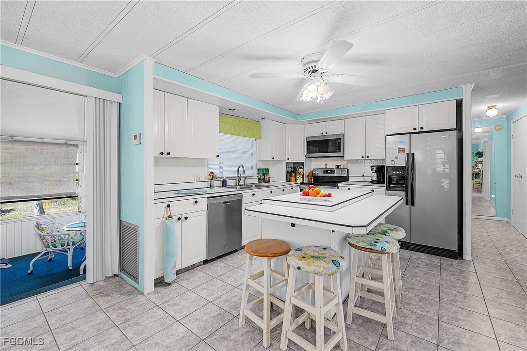 7696 Helen Road Bokeelia, FL 33922 - Photo 26 of 45 a kitchen with a refrigerator a sink and white cabinets