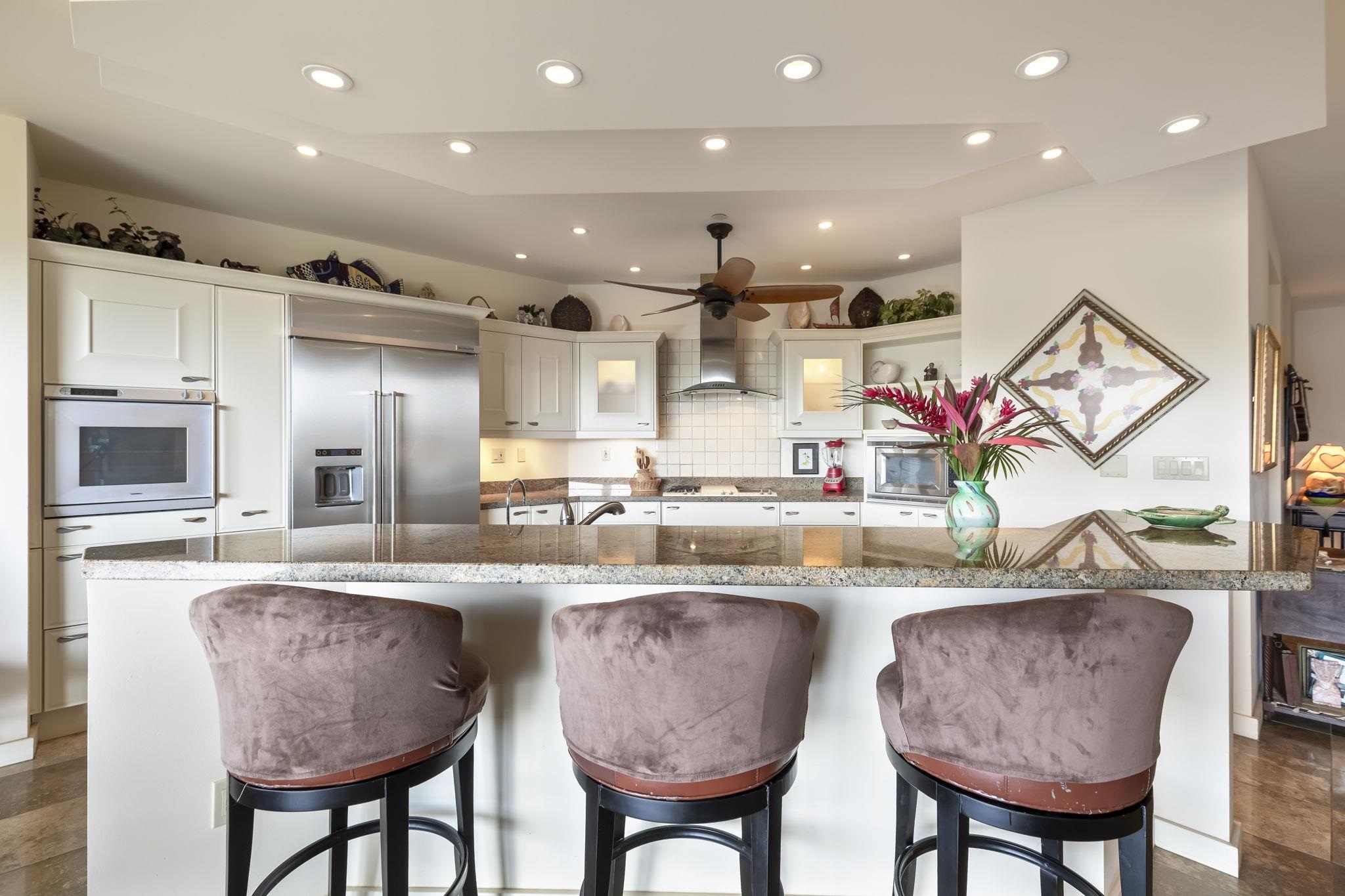 4955 Makena Road, Unit C302 Kihei, HI 96753 - Photo 8 of 37 a kitchen with stainless steel appliances granite countertop a kitchen island and chairs in it