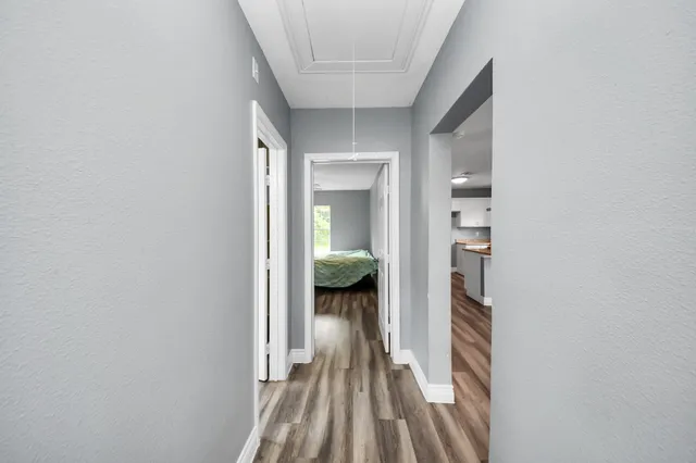 a view of a hallway with wooden floor and a bedroom