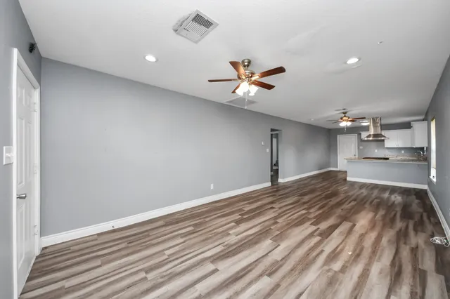 a view of empty room with wooden floor and fan