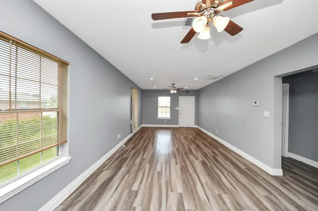 a view of empty room with wooden floor and fan