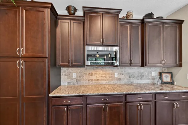 a kitchen with granite countertop a refrigerator a sink and wooden cabinets