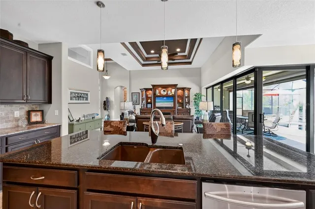 a kitchen with kitchen island a sink stainless steel appliances and living room view