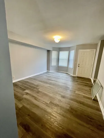 a view of an empty room with wooden floor and stairs