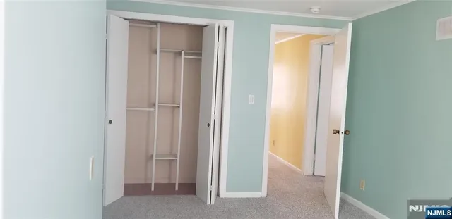 a view of an empty room with closet and mirror