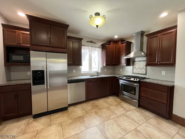 a large kitchen with stainless steel appliances granite countertop a stove a sink and a refrigerator