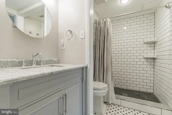 a bathroom with a granite countertop sink a toilet and shower