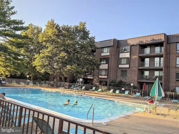 a view of swimming pool with outdoor seating and trees in the background