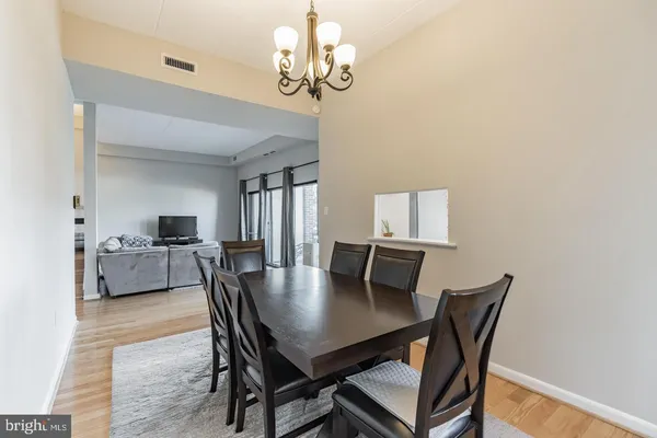 a dining room with wooden floor a chandelier a wooden table and chairs