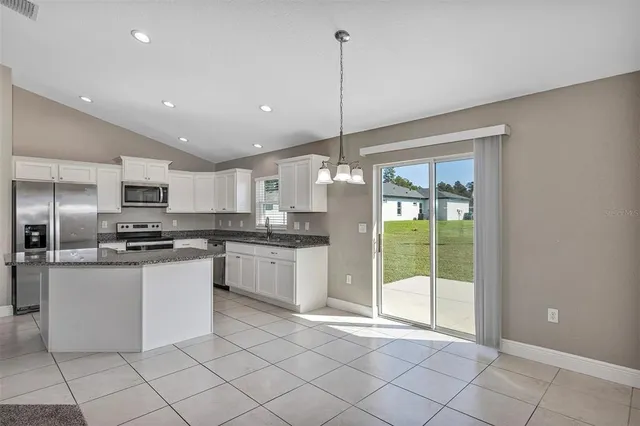 a kitchen with granite countertop white cabinets and a window