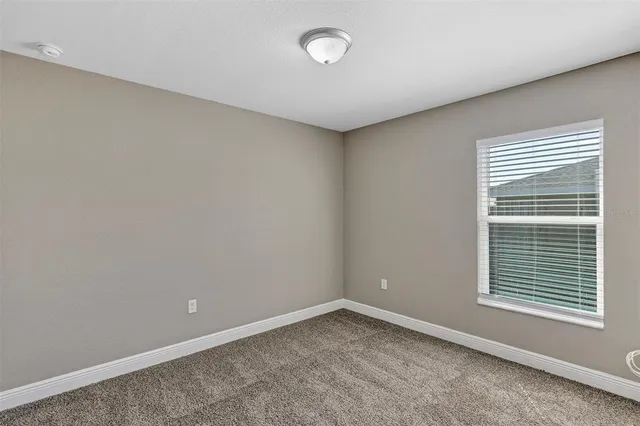 a view of an empty room with closet and a window