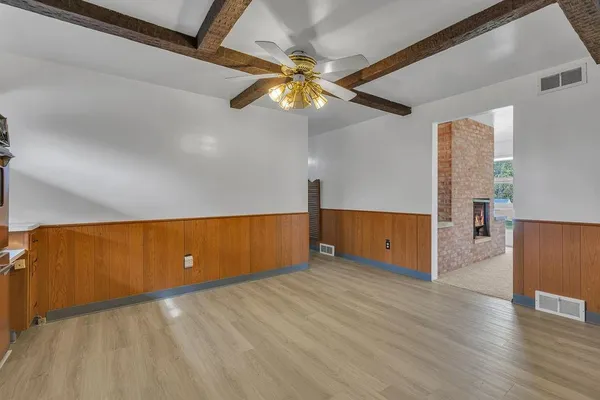 a view of an empty room with window and wooden floor