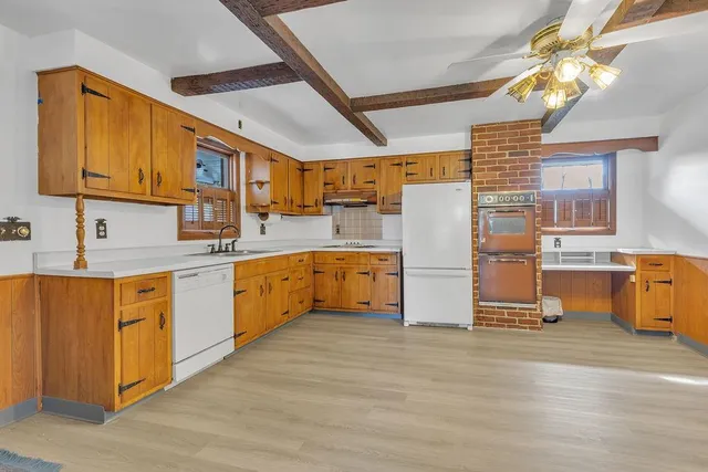 a kitchen with stainless steel appliances granite countertop a refrigerator oven a sink dishwasher and white cabinets with wooden floor