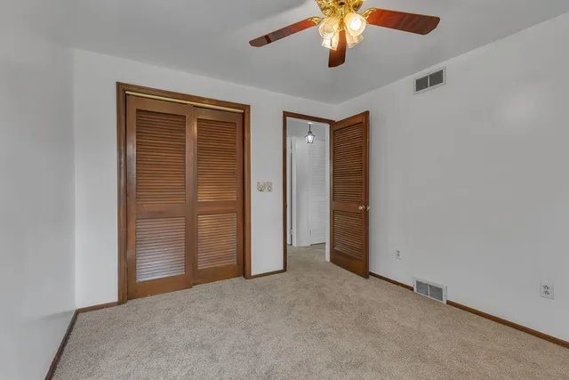 an empty room with closet and a chandelier fan