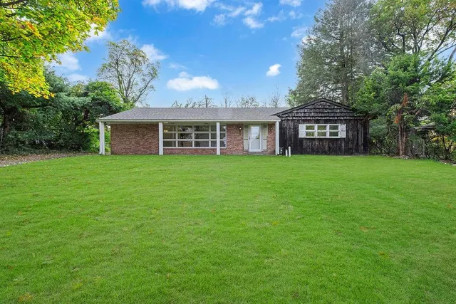 a view of a house with a yard and large trees