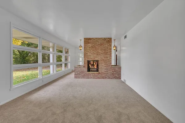 a view of an empty room with a fireplace and a window