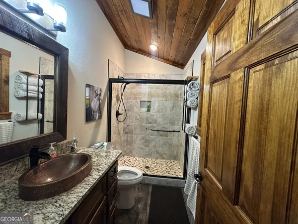 a bathroom with a granite countertop sink a mirror and shower