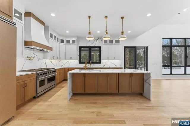 a large kitchen with a large counter top a sink stainless steel appliances and cabinets