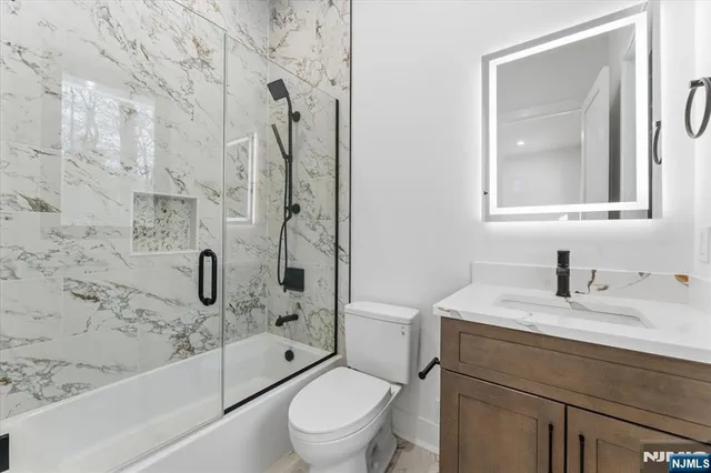 a bathroom with a granite countertop sink a toilet and shower