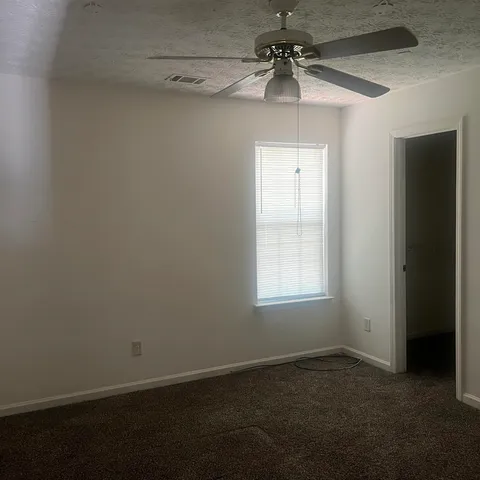 an empty room with a window and a fan
