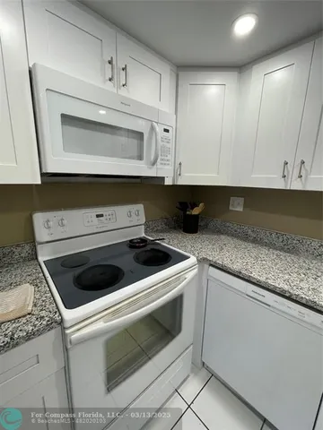 a kitchen with granite countertop white cabinets and white stove