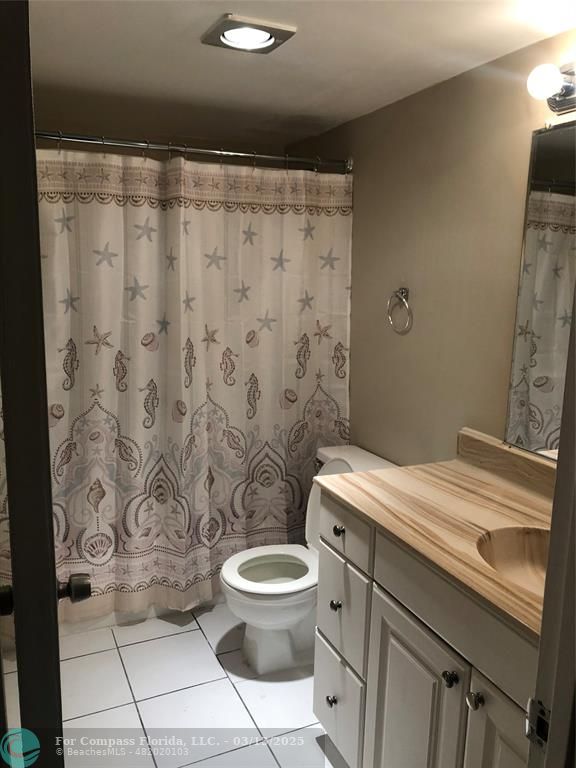 1400 Northeast 54th Street, Unit 203 Fort Lauderdale, FL 33334 - Photo 18 of 19 a bathroom with a granite countertop toilet a sink and a shower