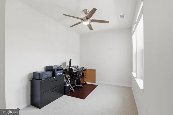 a view of a workspace with furniture and a ceiling fan