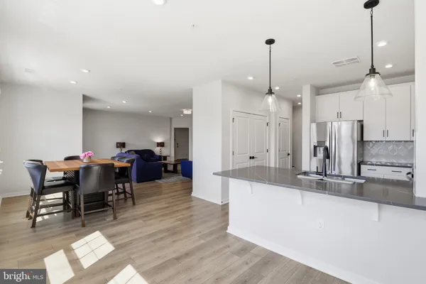 a view of a dining room and livingroom with furniture wooden floor a chandelier