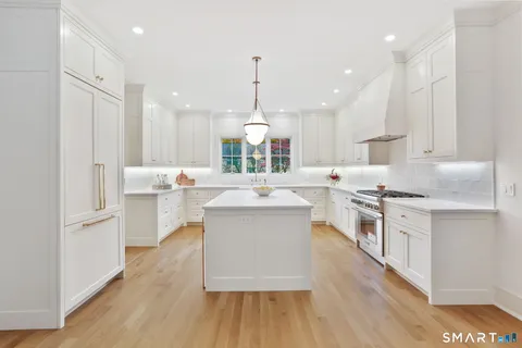 a large white kitchen with lots of counter space a sink appliances and cabinets