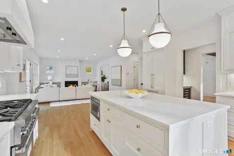 a large kitchen with stainless steel appliances a stove a sink dishwasher and a dining table with wooden floor
