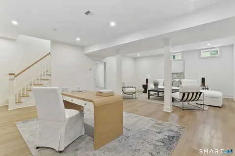 a living room with couches and kitchen view with wooden floor