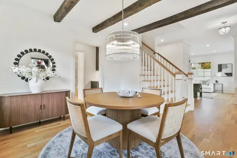 a dining room with wooden floor a chandelier a wooden table and chairs