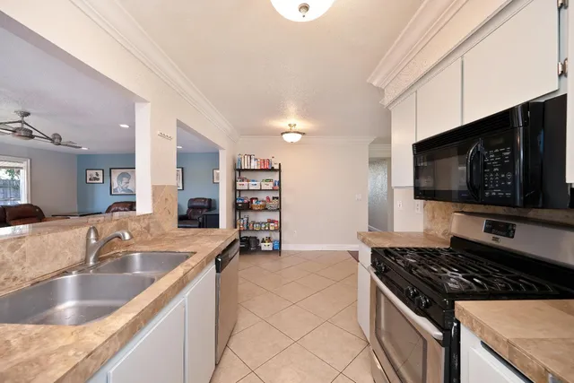 a kitchen with kitchen island granite countertop a stove top oven a sink dishwasher and a refrigerator with wooden floor