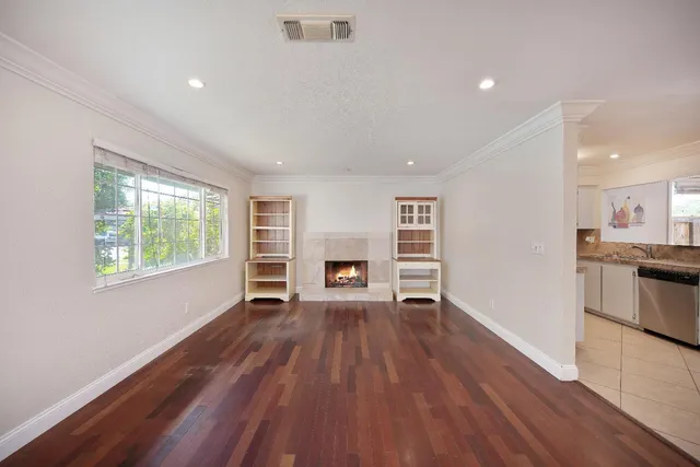 an empty room with wooden floor fireplace and windows