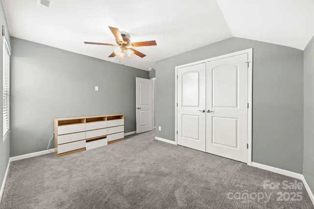 an empty room with closet and a ceiling fan