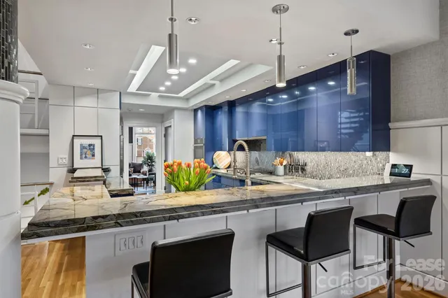 a kitchen with center island chandelier and living room view