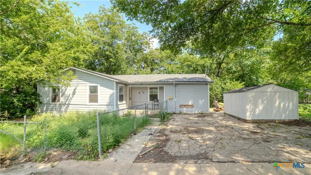 a view of a house with a yard and large trees