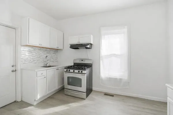 a kitchen with granite countertop a stove a sink and a white cabinets