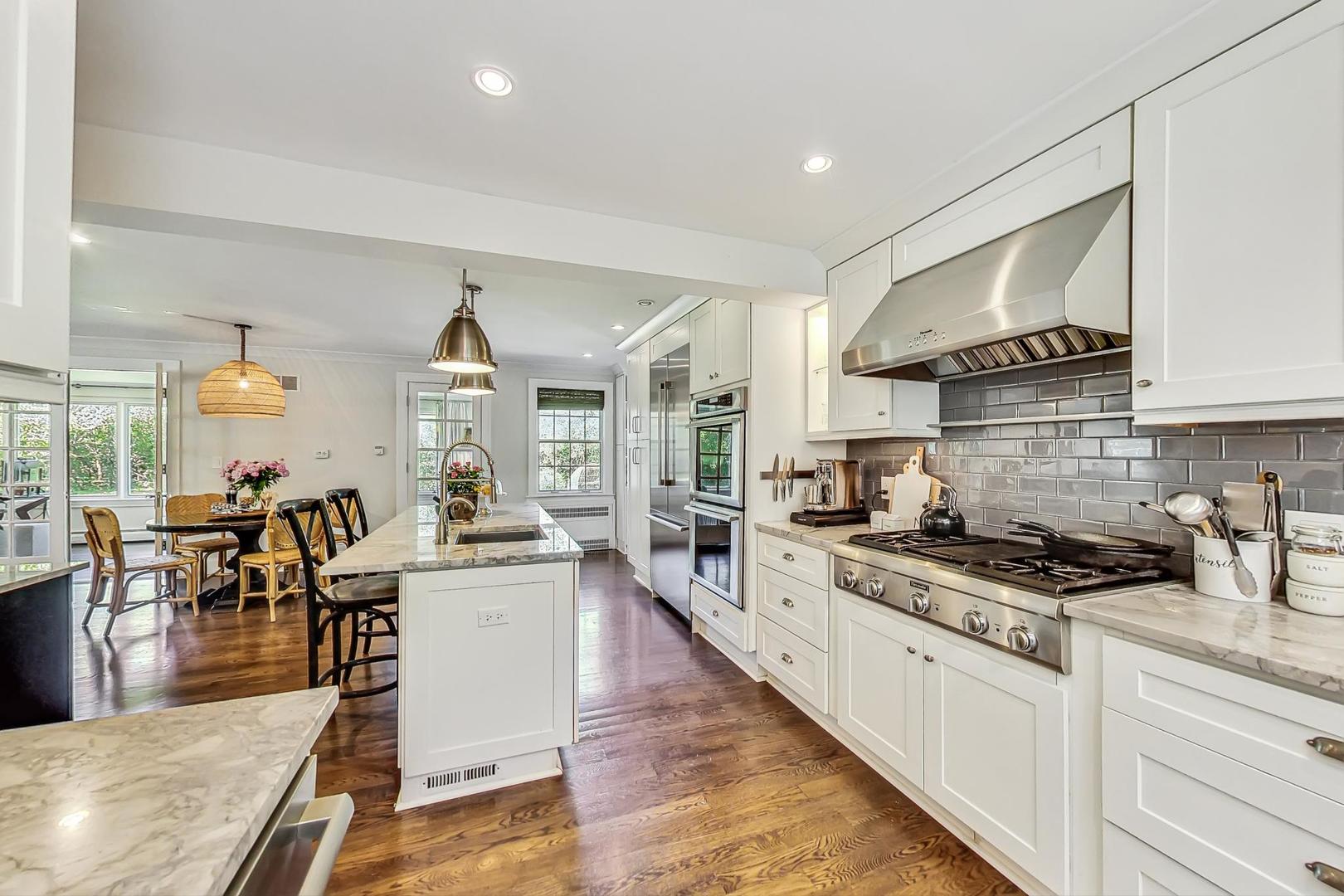 12 Timber Lane Northbrook, IL 60062 - Photo 7 of 28 a kitchen with stainless steel appliances a stove a sink a kitchen island with a dining table and chairs