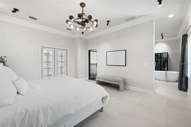 a spacious bedroom with a bed and a chandelier