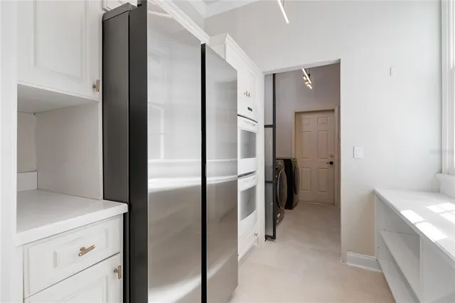 a kitchen with a refrigerator and white cabinets