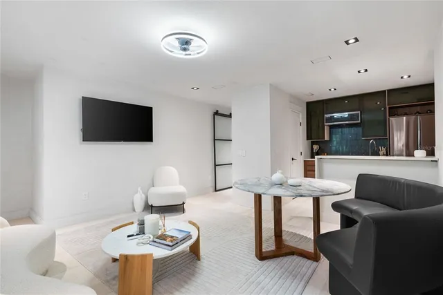 a living room with furniture a flat screen tv and kitchen view