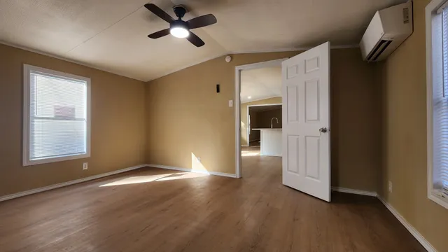 an empty room with wooden floor cabinet and windows