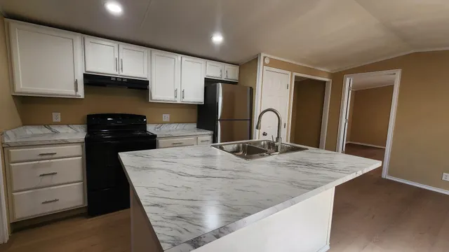 a kitchen with granite countertop white cabinets and refrigerator