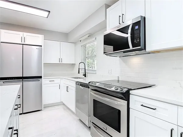 a kitchen with stainless steel appliances white cabinets white stove a microwave and a refrigerator