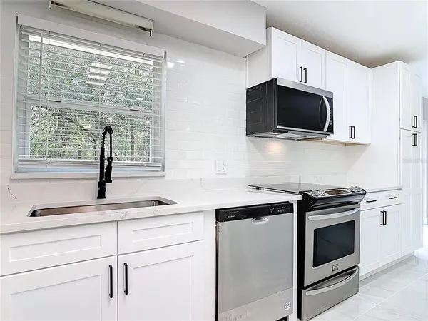 a kitchen with white cabinets a sink and a stove