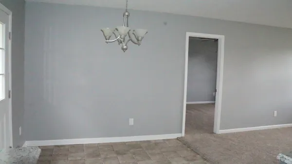 an empty room with chandelier fan