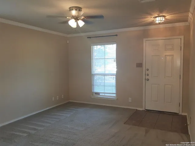 en empty room with chandelier fan and windows