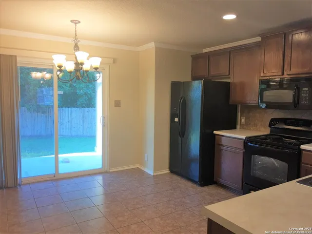 a kitchen with kitchen island granite countertop wooden cabinets and refrigerator